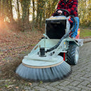 Person operating a Westermann CM2 PRO Ride-On machine, to remove moss and debris from block paving