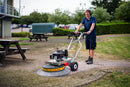 Person using a Westermann WR870 Moss Brush to clear moss from block paving, on commercial grounds