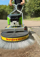 Person using a Westermann Moss Brush alongside a curb