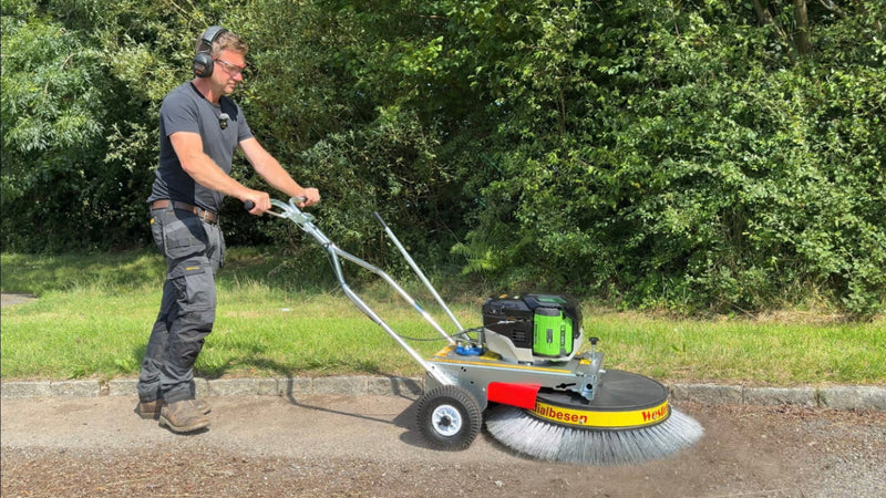Person using a Westermann Moss Brush on tarmac