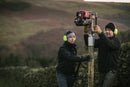 2 people installing a post with the Easy Petrol Post Driver, in a countryside setting