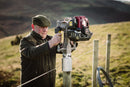 A person installing a post with the Easy Petrol Post Driver, in a countryside setting