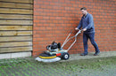 A person using a Westermann WR870 Moss Brush to clear moss from block paving