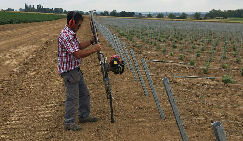 Ground anchor being installed on a vineyard to anchor the trellis, using easy petrol post driver